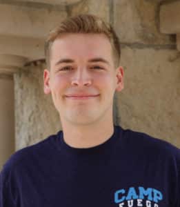 Young man smiling at the camera wearing a blue t-shirt with the text "Howard Payne University". | HPU