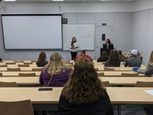 A lecture in progress at Howard Payne University with a presenter speaking to an audience in a classroom setting. | HPU
