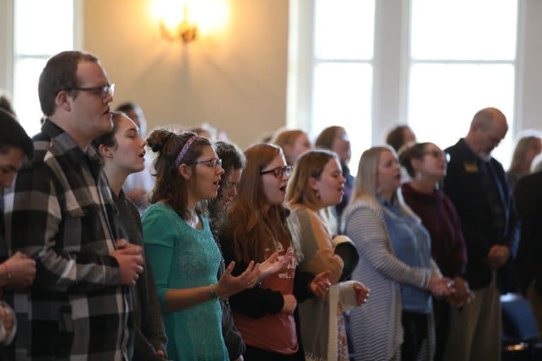 Group of people standing and singing in Howard Payne University's church. | HPU