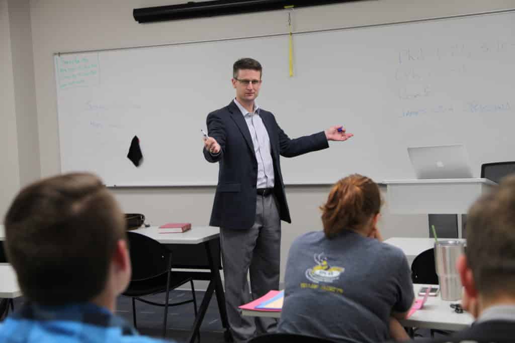 A Howard Payne University teacher gesturing while speaking to a classroom of students. | HPU