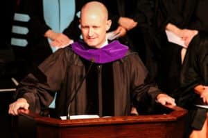 A speaker in academic regalia standing at a podium during a graduation ceremony at Howard Payne University. | HPU