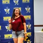 Woman smiling in front of a backdrop with the Howard Payne University logo. | HPU
