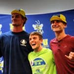Three young men from Howard Payne University posing with medals and smiling, two wearing baseball caps and one in a bright green shirt. | HPU