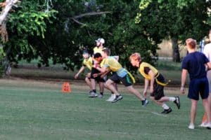 Group of Howard Payne University students playing flag football outdoors at dusk. | HPU
