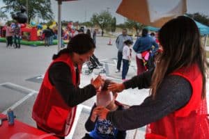 A volunteer from Howard Payne University applying face paint to a child at a community outdoor event. | HPU