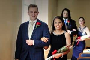 A couple holding hands and smiling at a formal event at Howard Payne University, with two people in the background. | HPU