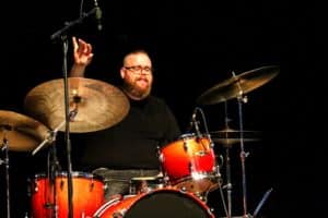 Drummer from Howard Payne University in mid-performance with drumsticks raised. | HPU