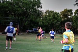 A group of Howard Payne University students playing a casual game of touch football in an outdoor field at dusk. | HPU
