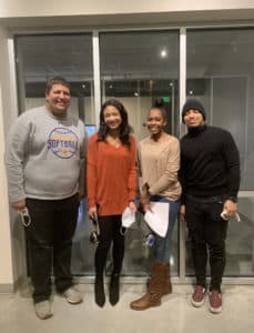 Four individuals posing for a photo indoors near a glass door at Howard Payne University. | HPU