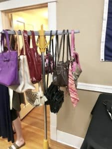 Assorted bags and accessories hanging on a coat rack in a Howard Payne University room. | HPU