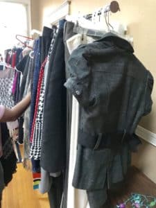 A variety of clothes hanging on a rack in a Howard Payne University dorm room, with a denim jacket featured prominently in the front. | HPU