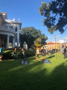 People gathered on a lawn at Howard Payne University with a large inflatable yellow character balloon in the background. | HPU