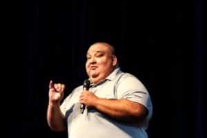 A man speaking on stage at Howard Payne University with a microphone in hand. | HPU