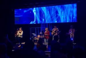 A band performing on stage with a blue-lit background at Howard Payne University. | HPU