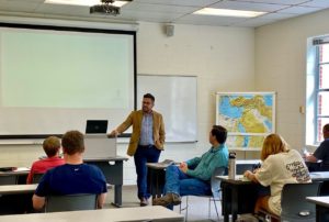 Lecturer interacting with students in a Howard Payne University classroom setting. | HPU