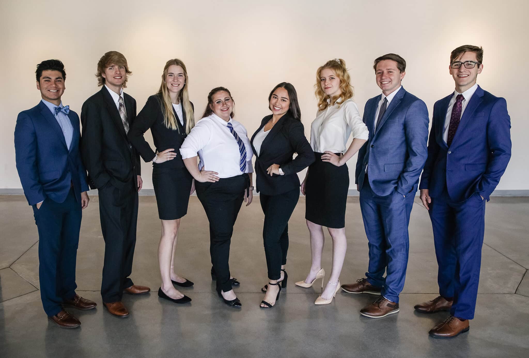 Group of seven professionals in Howard Payne University business attire standing confidently. | HPU