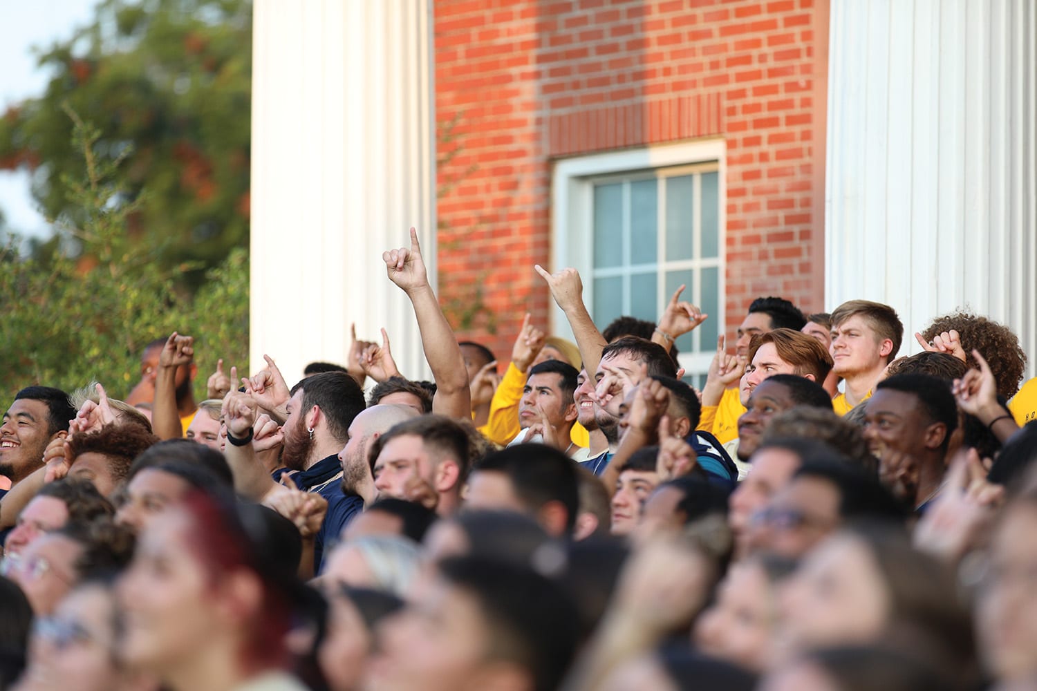 A crowd of Howard Payne University students pointing and looking in the same direction with expressions of excitement or anticipation. | HPU