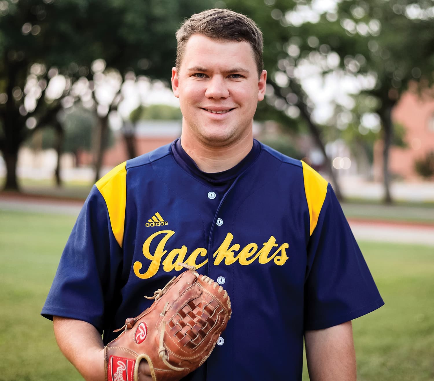 Baseball player from Howard Payne University holding a glove and smiling at the camera. | HPU