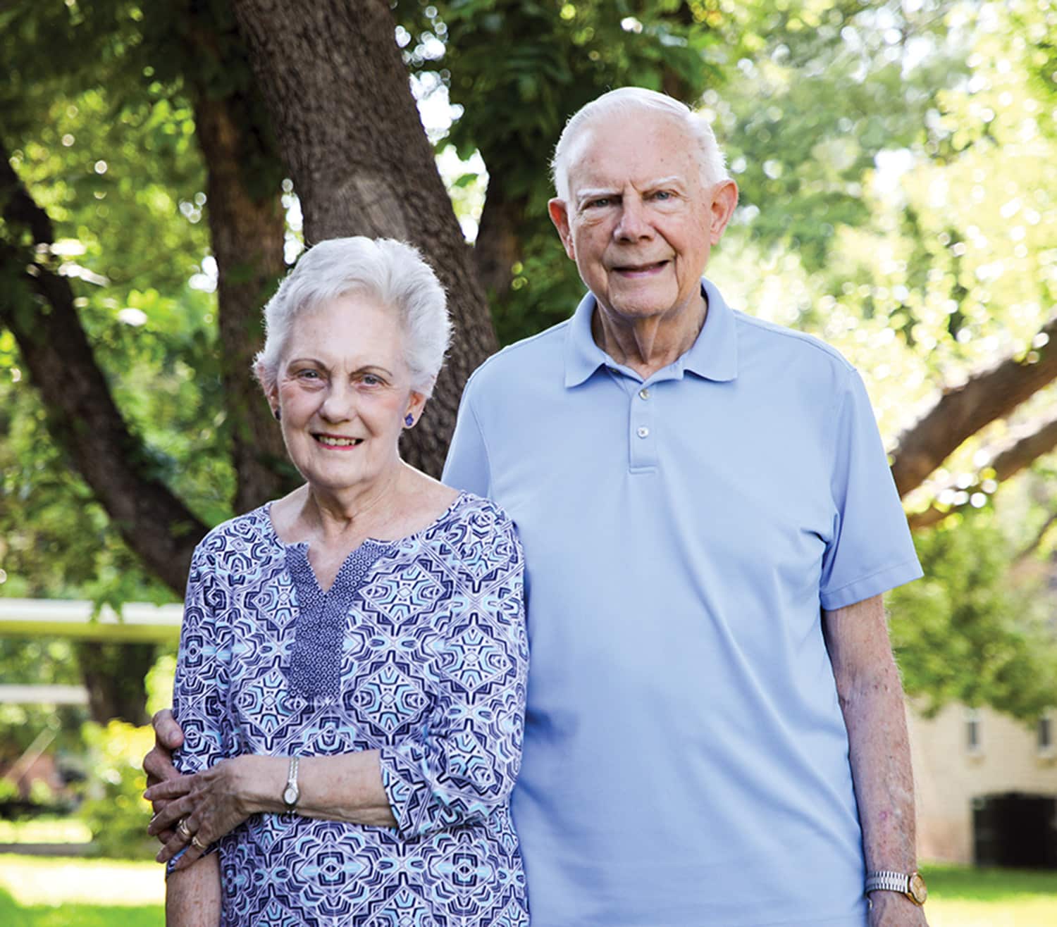 Elderly couple standing together outdoors with Howard Payne University's trees in the background. | HPU