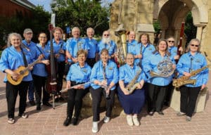 Group of senior musicians from Howard Payne University posing with their instruments, wearing matching blue shirts with a logo. | HPU
