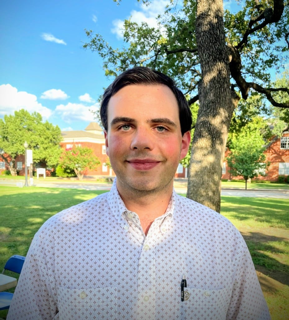 A man smiling outdoors with Howard Payne University and trees in the background. | HPU