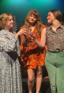 Three individuals in Howard Payne University vintage clothing holding champagne glasses and toasting. | HPU