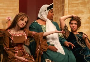 Three actresses sit appear on stage during a scene in the play "Poor Clare."