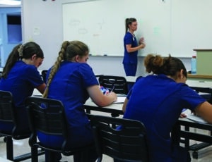 High School student's sit at a desk taking notes while Dr. Laci Sutton instructs them during the Health Science Enrichment Workshop.